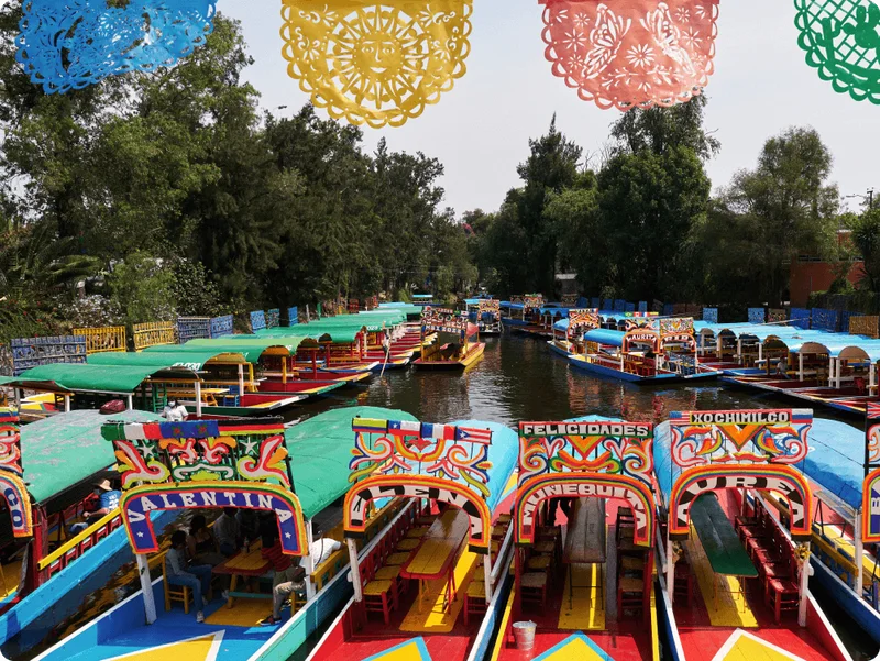 Image Description: Rows of brightly-colored canal barges at the Floating Gardens of Xochimilco in Mexico City