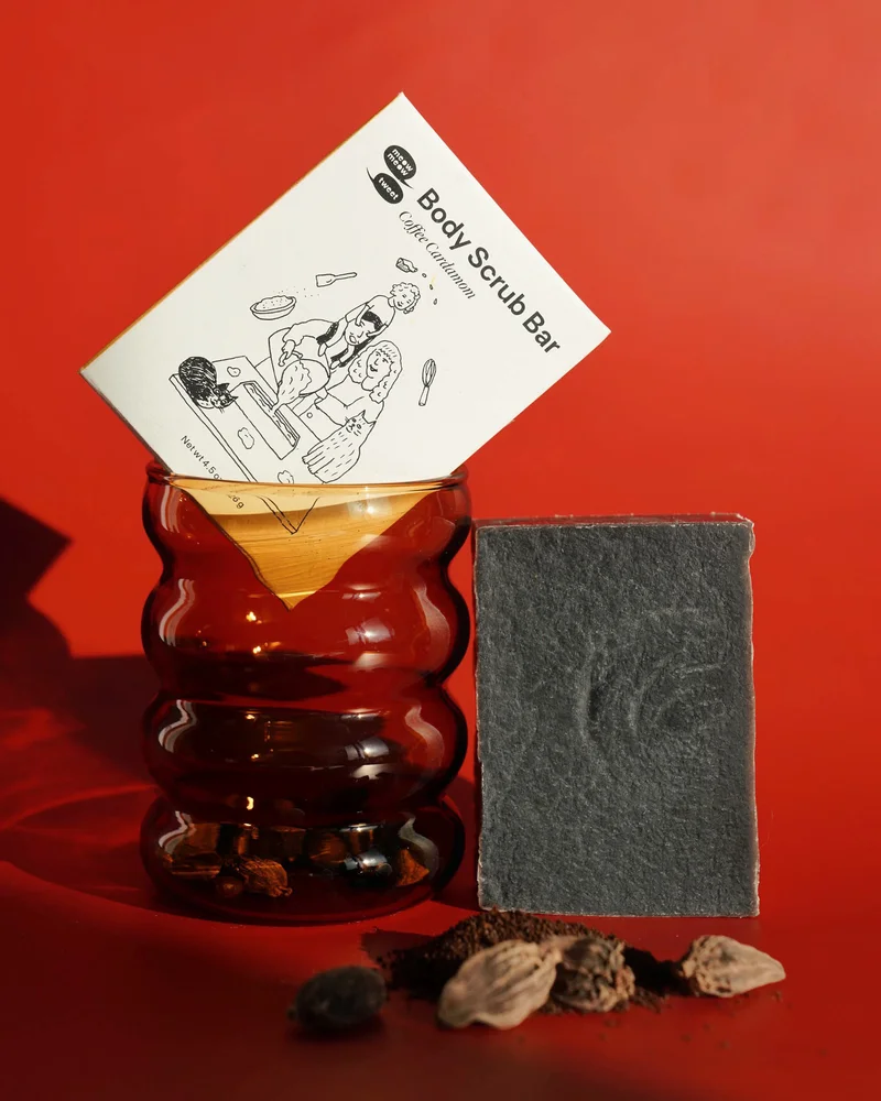 A dark brown bar of soap sits beside a brown cup on a red background