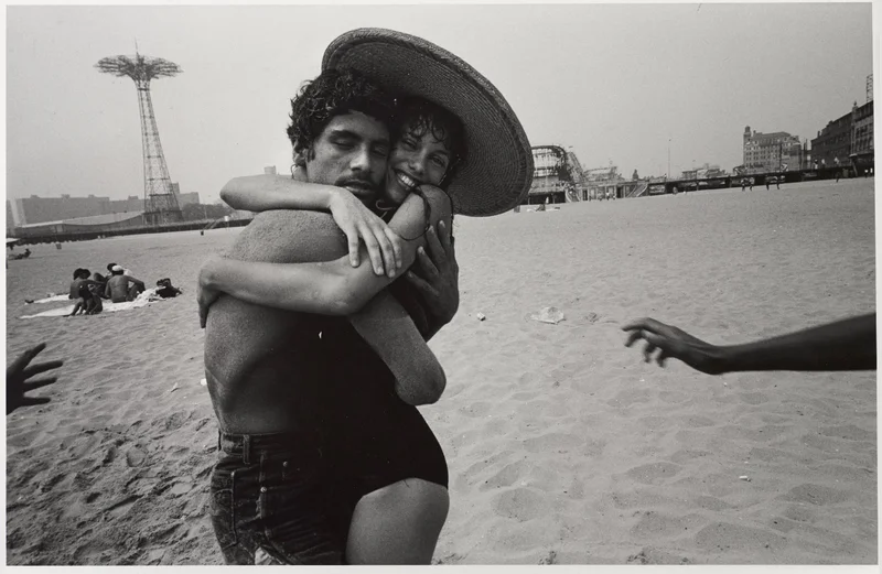 Black-and-white photograph of two people hugging on a beach