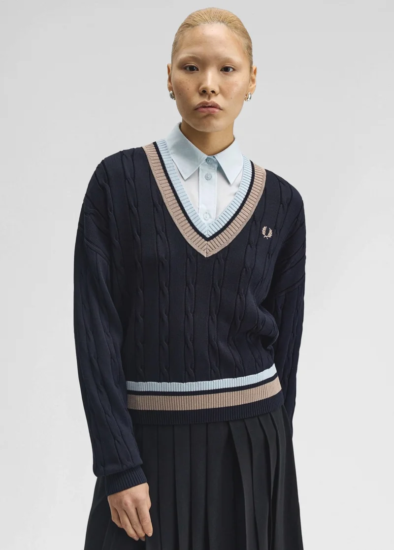 A female model wearing a Fred Perry Bold Tipped Cable Knit Jumper in Navy