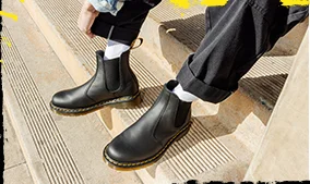 Leg down shot of someone cuffing their pants wearing 2976 boots