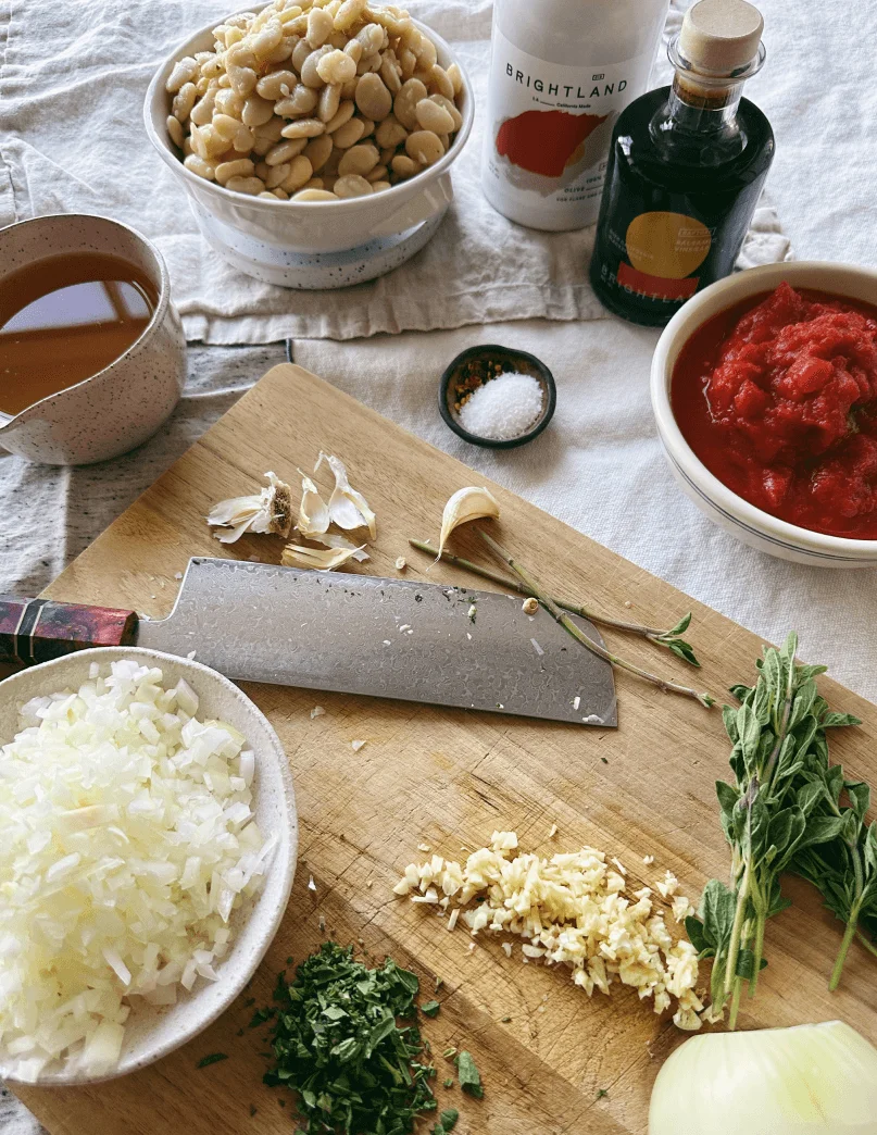 Various chopped ingredients and food items in a prep bowl around a cutting board and knife
