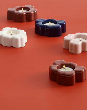 Assortment of Unikko tea lights lit on table.