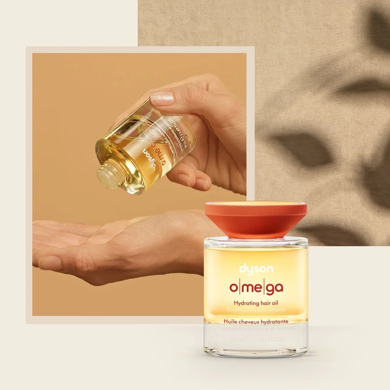 Dyson Omega Hydrating hair oil is dispensed into the palm of a hand.