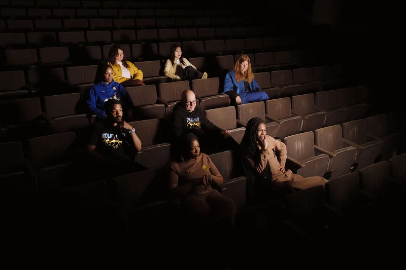 seven people sitting in auditorium seating