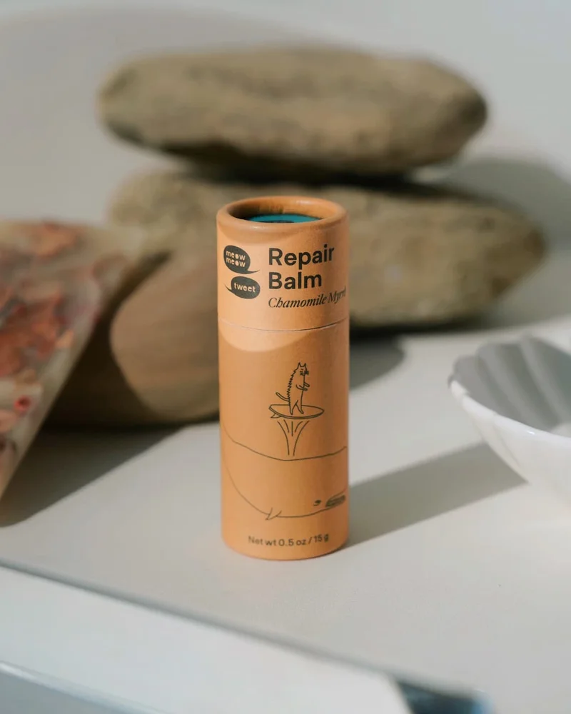 A brown paper tube sits on a white counter with rocks stacked behind it