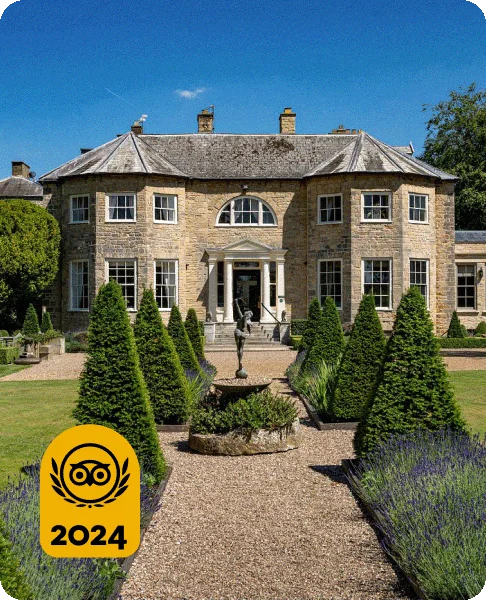 Image Description: A pebble walkway lined with green bushes and lavender leading to a brick townhouse. A statue holding a bow and arrow is in the middle of the walkway. A gold 2024 Travelers’ Choice Awards Best of the Best badge is on the bottom left corner of the image.