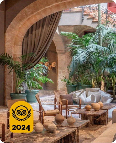 Image Description: An earth tone lobby with large, airy doorways leading to a courtyard with green plants and a fountain. A gold 2024 Travelers’ Choice Awards Best of the Best badge is on the bottom left corner of the image.