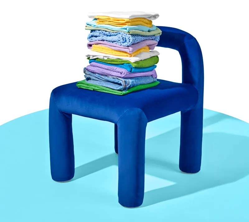 A chunky blue chair with nicely folded laundry