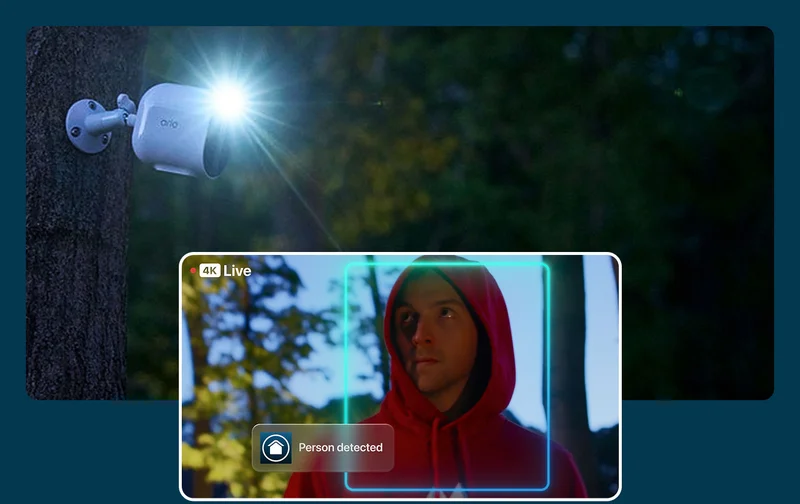 Arlo security camera with the integrated spotlight turned on at night. A simulated point of view image shows a burglar. Person detected.