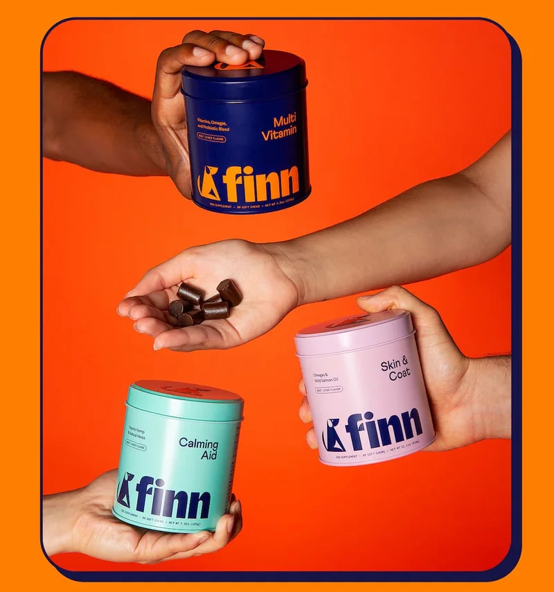 Lifestyle photograph of four human arms reaching into the frame, holding various Finn products against an orange seamless background.