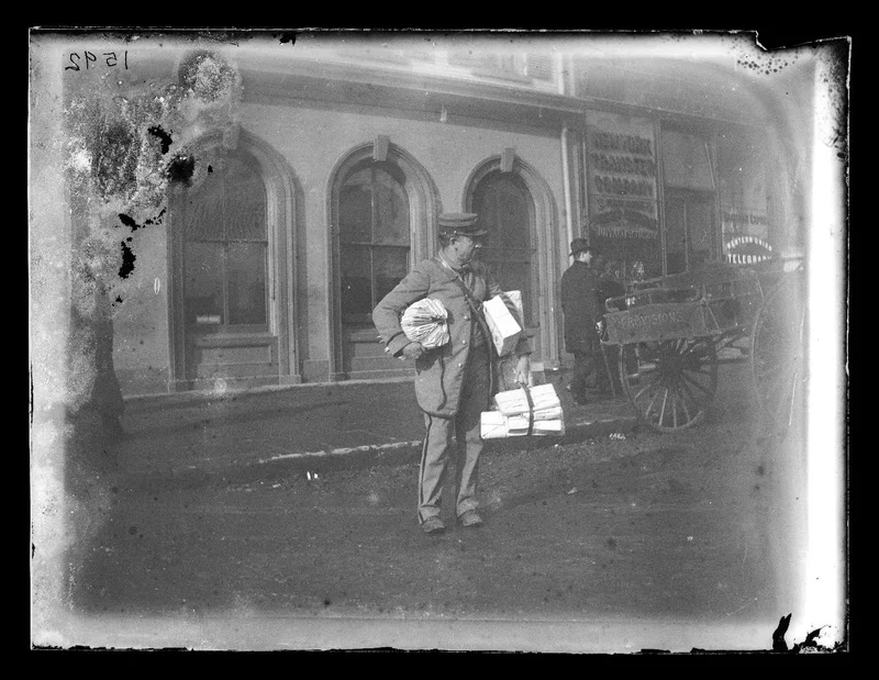 Black-and-white photograph of a mail carrier with lots of packages