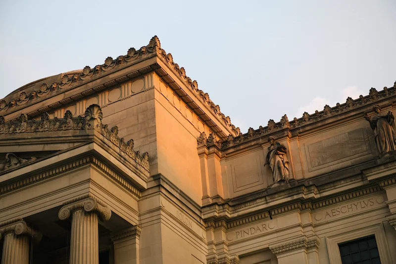 The exterior of the Brooklyn Museum lit in soft sunlight