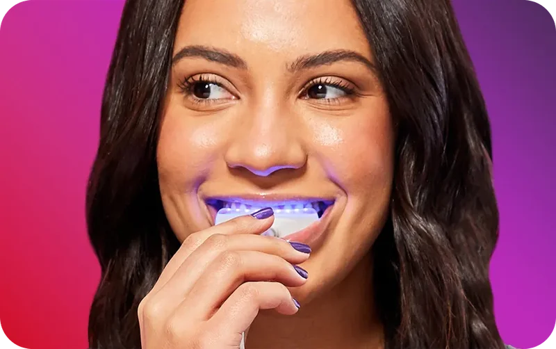 Image of woman using Colgate® Optic White® ComfortFit LED Teeth Whitening Kit