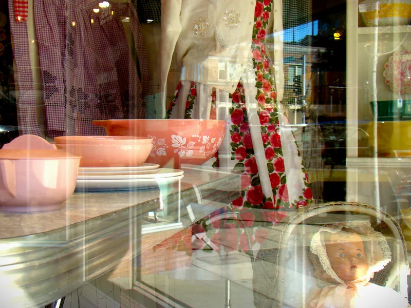 A photograph of a store window with plates and dolls