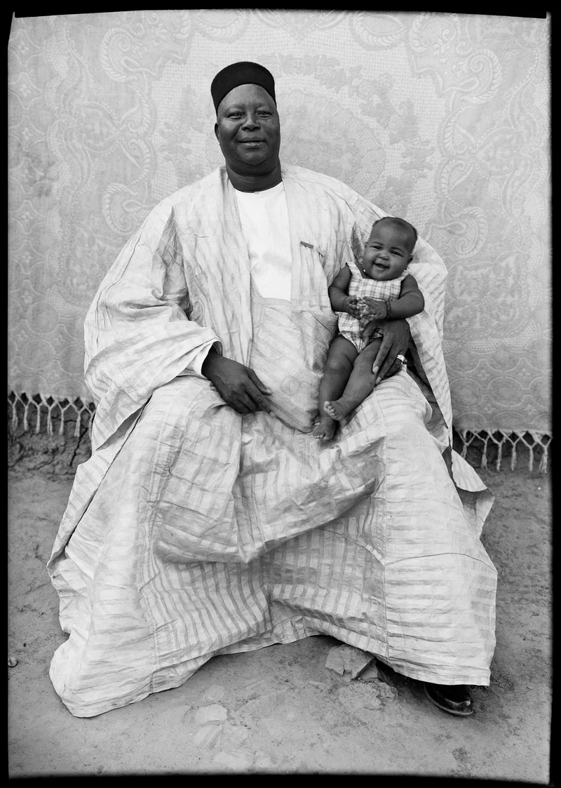 A photo of a man with a smiling baby on his knee