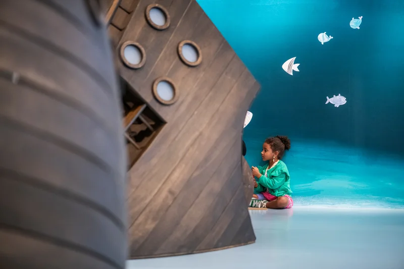 A child behind a ship sculpture