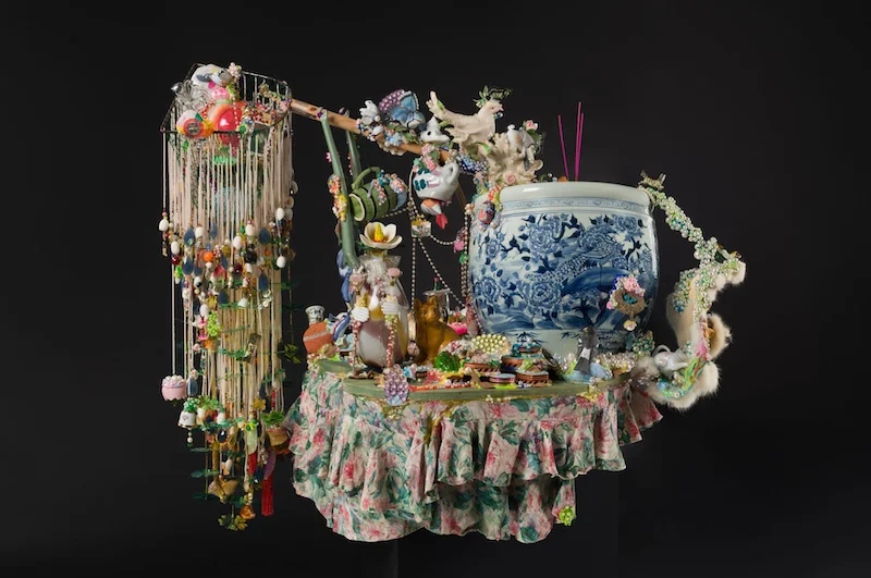 A sculpture made of glass beads, fur, porcelain, beads, silk, plastic decor, and more