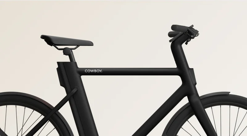 Close-up side view of a Cowboy e-bike, showcasing its minimalist frame design, integrated cockpit, and sleek black matte finish.