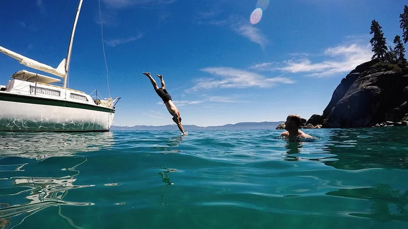 Image description: Man diving off of boat into Lake Tahoe