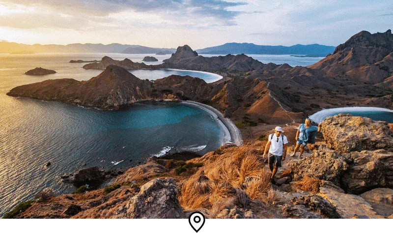 Image Description: Two travelers trekking to the viewpoint at the top of Padar Island in Komodo National Park at sunset
