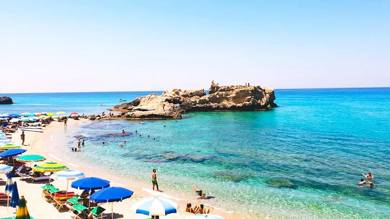 Image description: People relaxing on the beach in Tropea, Italy.