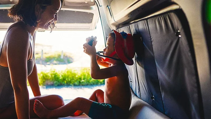 Image description: Toddler playing with Mom, in the back of a van.