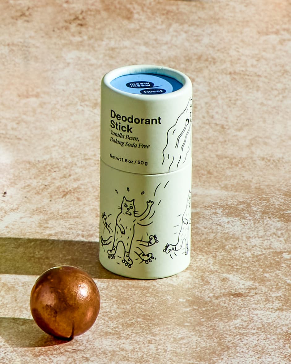 A light green deodorant stick on a tan background with a bronze ball