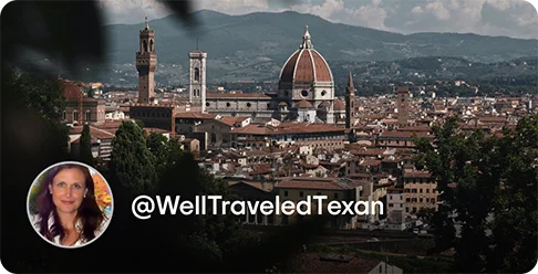 Image Description: A city with a cathedral and hills in the background. A profile photo of a person smiling and the handle @WellTraveledTexan is on the bottom left corner of the image.