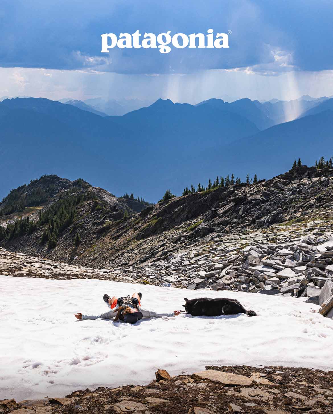 Patagonia. A trail runner lays on a mountain snowfield with a dog.