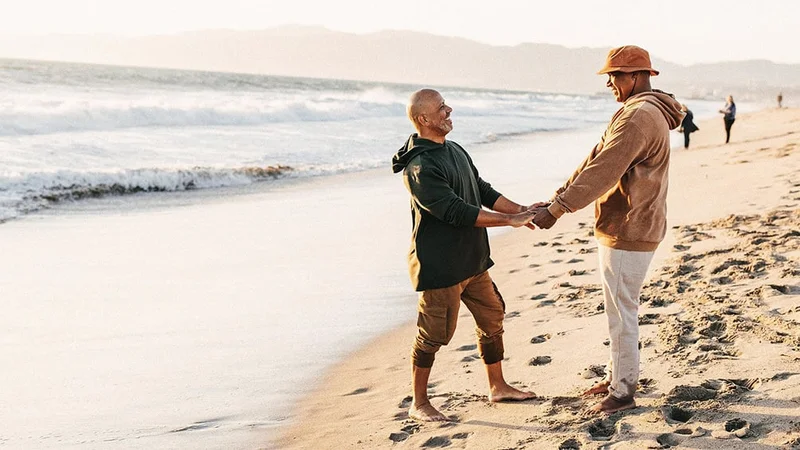 Image description: Mature couple holding hands on the beach