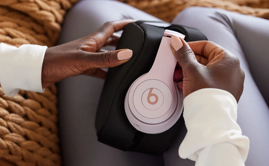 Woman taking Beats Solo 4 headphones out of the carrying case