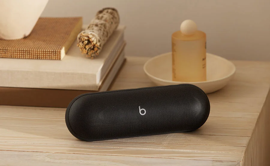 Beats Pill speaker in Matte Black shwon on a bedside table showcasing it's powerful portability