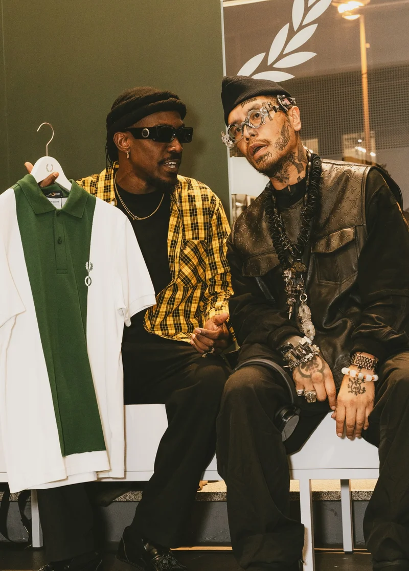 Two men are engaged in conversation at our Craig Green event in Berlin, while one of them holds up a polo from the new Craig Green collection.
