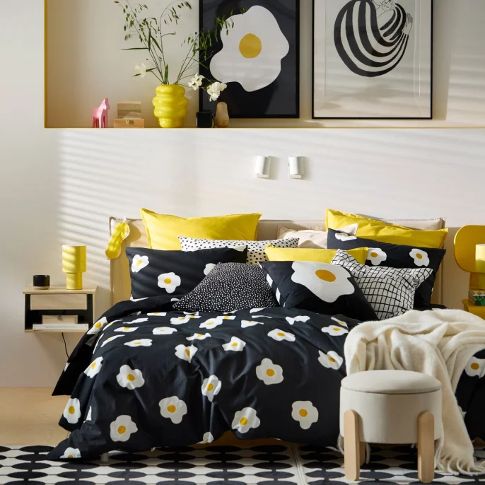 A bed dressed in black patterned ÖGONLOCKSMAL bedding.