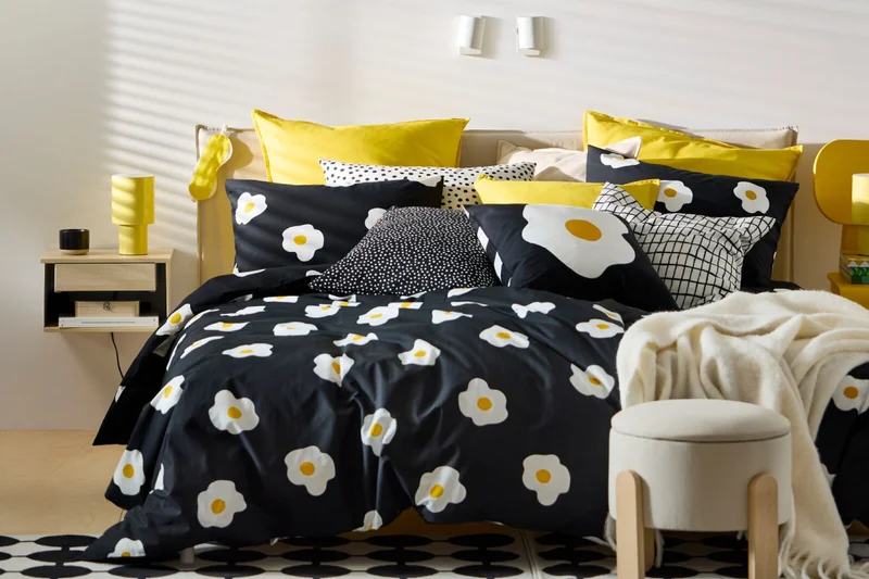 A bed dressed in black patterned ÖGONLOCKSMAL bedding.