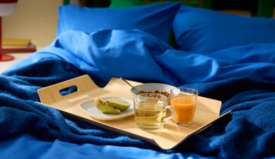 A SILVERHAJMAL tray on top of a bed dressed in blue bedding.