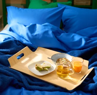 A SILVERHAJMAL tray on top of a bed dressed in blue bedding.