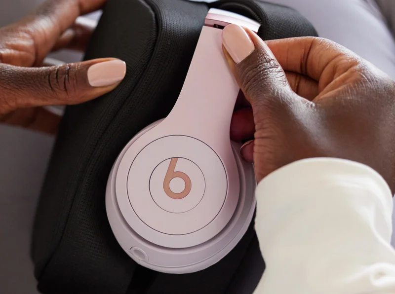 Powerbeats Fit earbuds in Power Pink floating above charging case