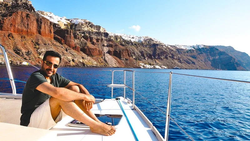 Image description: Man on yacht sailing through Amoudi Bay, Santorini, Greece.