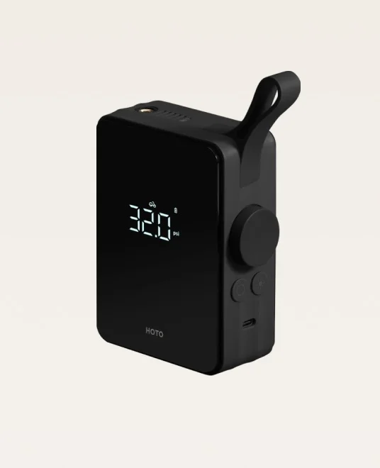 A render. A compact black HOTO air compressor with a digital display, handle, and control buttons on the side.