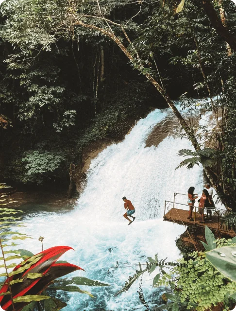 Image Description: A male traveler jumping into a waterfall at Ocho Rios in Jamaica