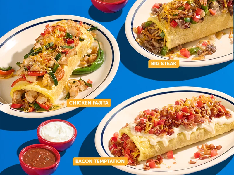 An assortment of IHOP Stuffed ‘N Stacked Omelettes on plates against a blue background, including the Big Steak and Chicken Fajita