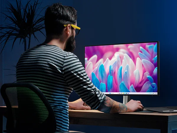 A designer working with a 3D modelling program on a Dell laptop and monitor.