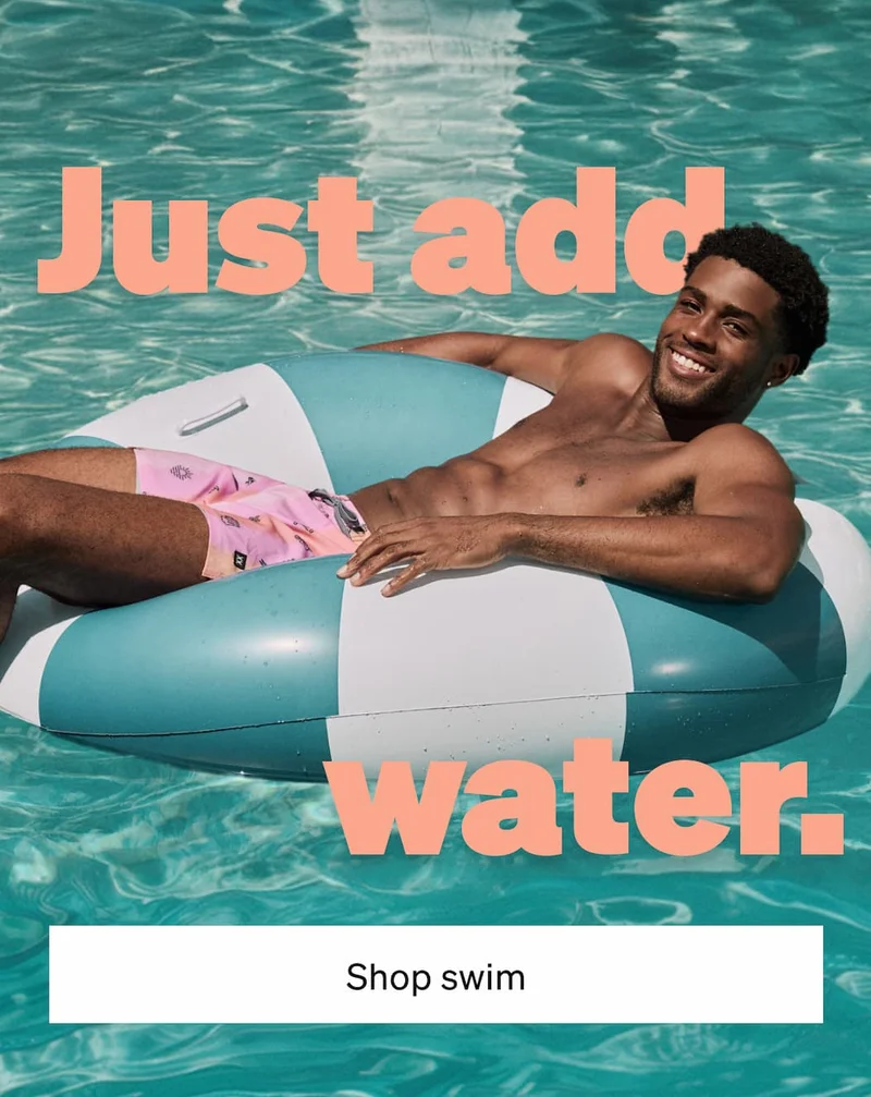 Smiling man floating in a pool wearing pink swim shorts beside text “Just add water” with Shop Swim button.