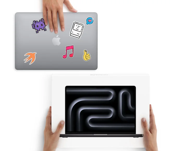 Used MacBook Pro, silver color, closed lid covered in various stickers, being traded in for a new MacBook Pro, space black color, with Liquid Retina XDR display in box