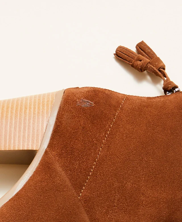Close-up of tan suede Ingrid bootie with tassel and Hush Puppies logo. Shop boots.