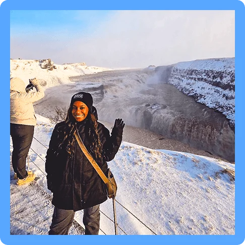 Image Description: Woman smiling and posing in front of a large snow-covered natural formation.