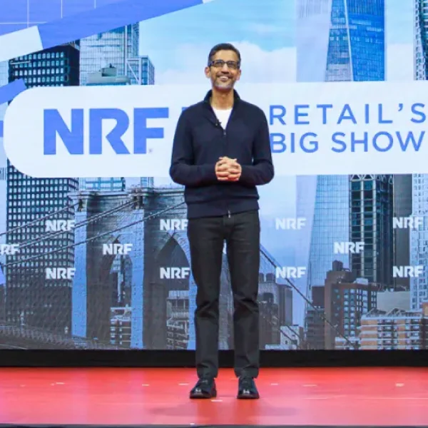 Sundar Pichai stands on a stage in front of a large banner for NRF Retail's Big Show, featuring a cityscape graphic and NRF logos in the background.