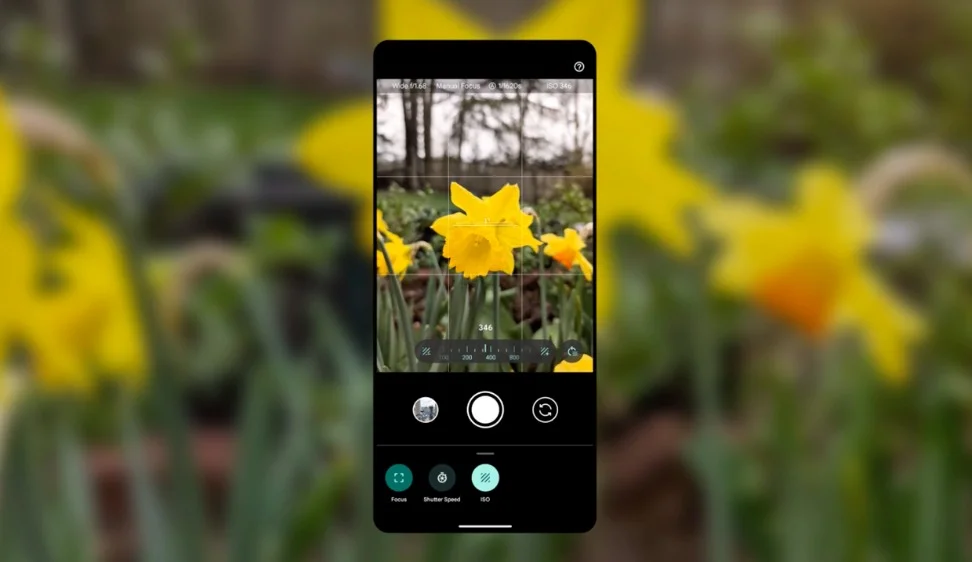 A blurry photo of yellow flowers. A Pixel phone is overlaid on top showing the camera open with Pro Controls open and the flowers in focus.